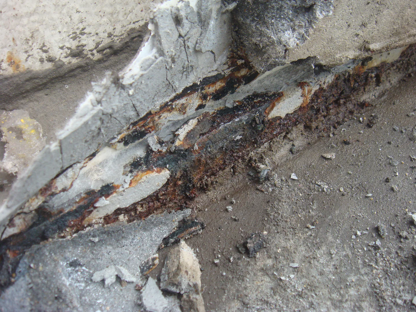 Corroded and deteriorated storage tank base edge before protection.