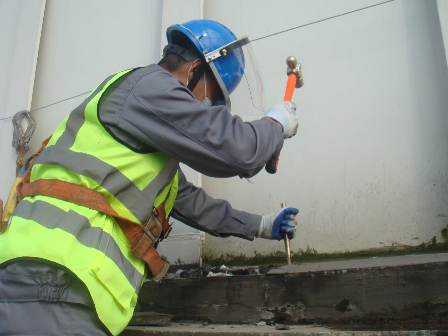 Project personnel inspecting the storage tank edge interface before material application.