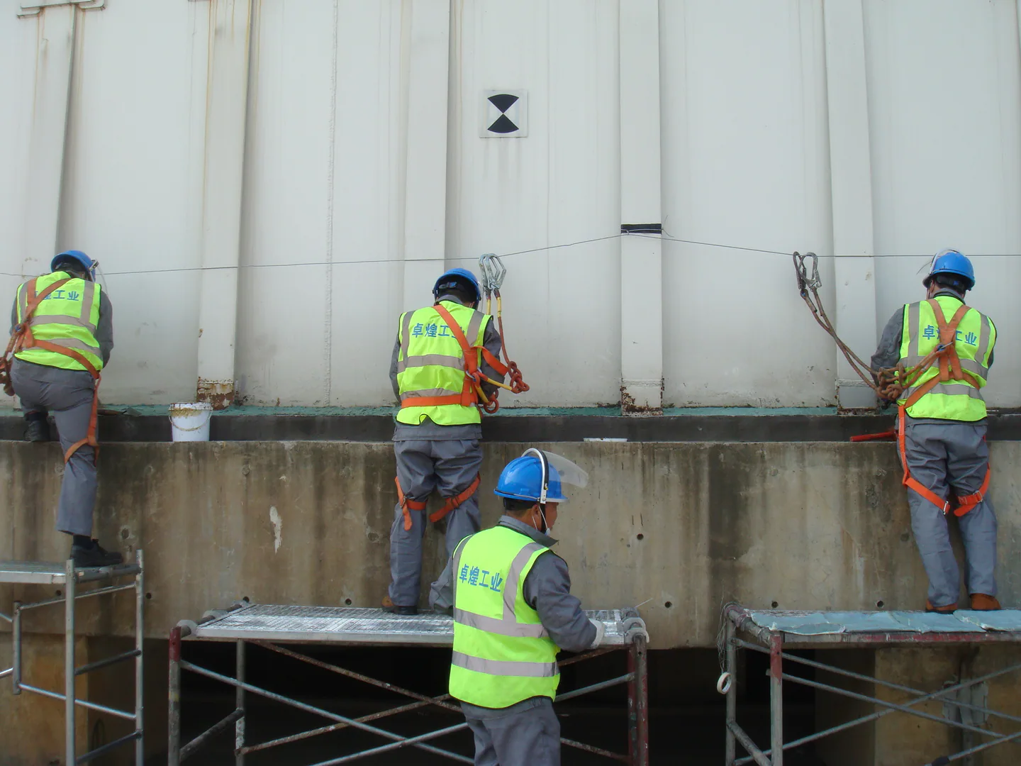 Installation team applying the corrosion protection system around the storage tank edge.